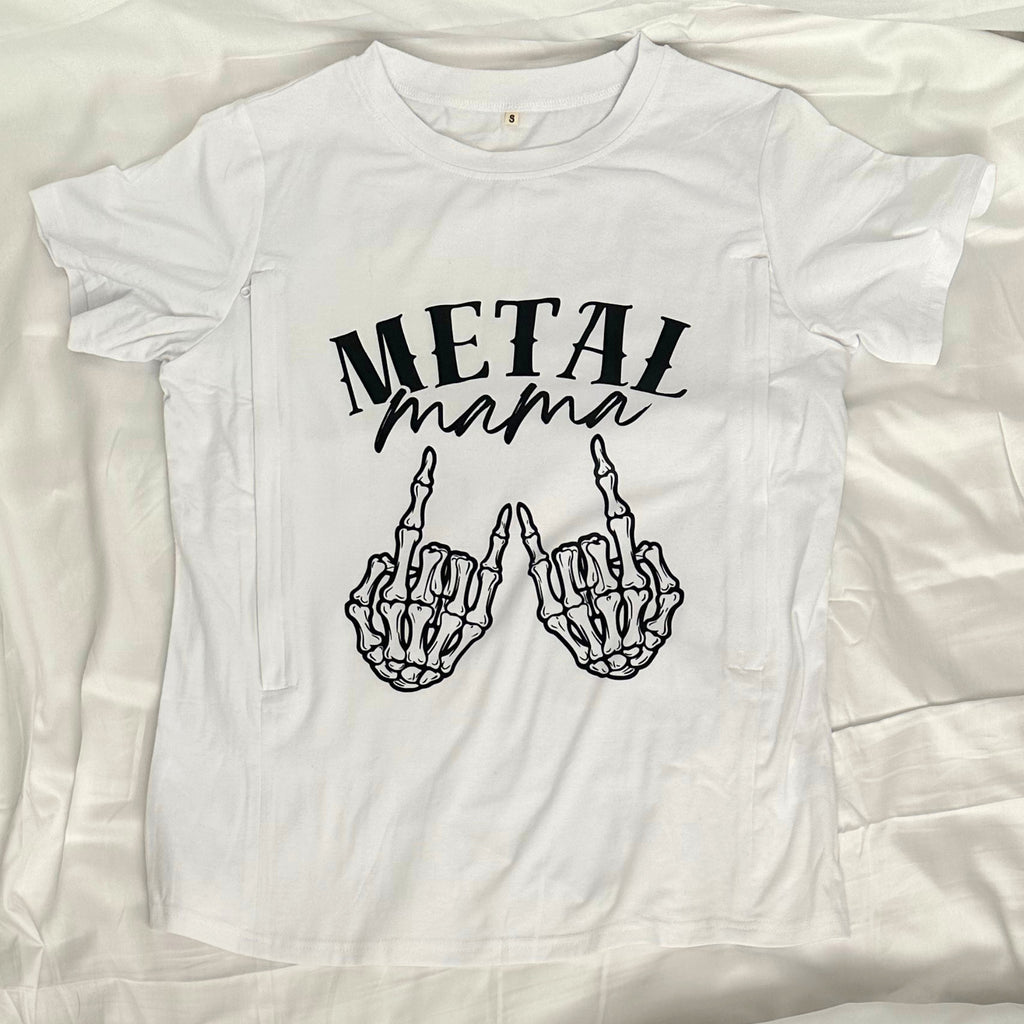 A white short-sleeve t-shirt laid flat on a white fabric background, featuring a black graphic print that reads 'METAL mama' above two skeletal hands making the rock on gesture.