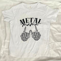 A white short-sleeve t-shirt laid flat on a white fabric background, featuring a black graphic print that reads 'METAL mama' above two skeletal hands making the rock on gesture.